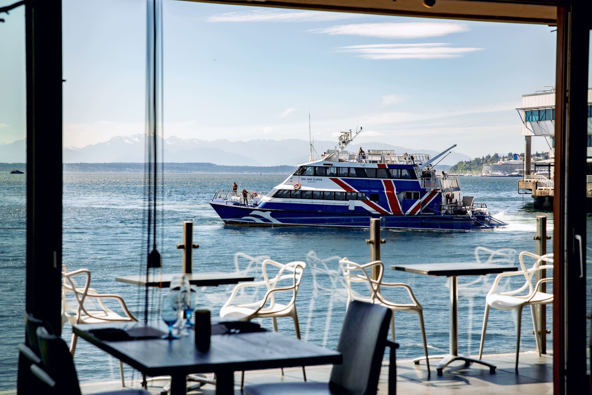 A patio ay The Edgewater facing the water with a large boat in the water.