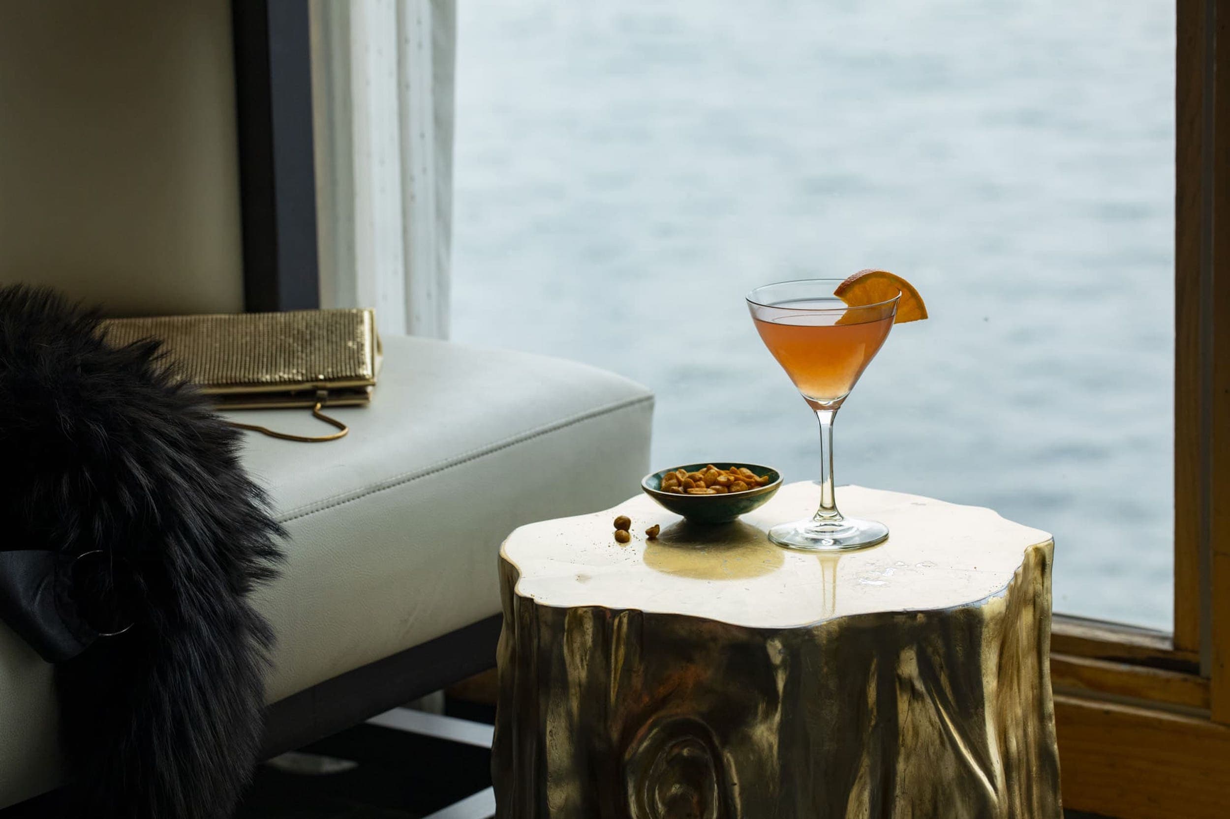 A cocktail and peanuts on a wood block table in a suite at The Edgewater