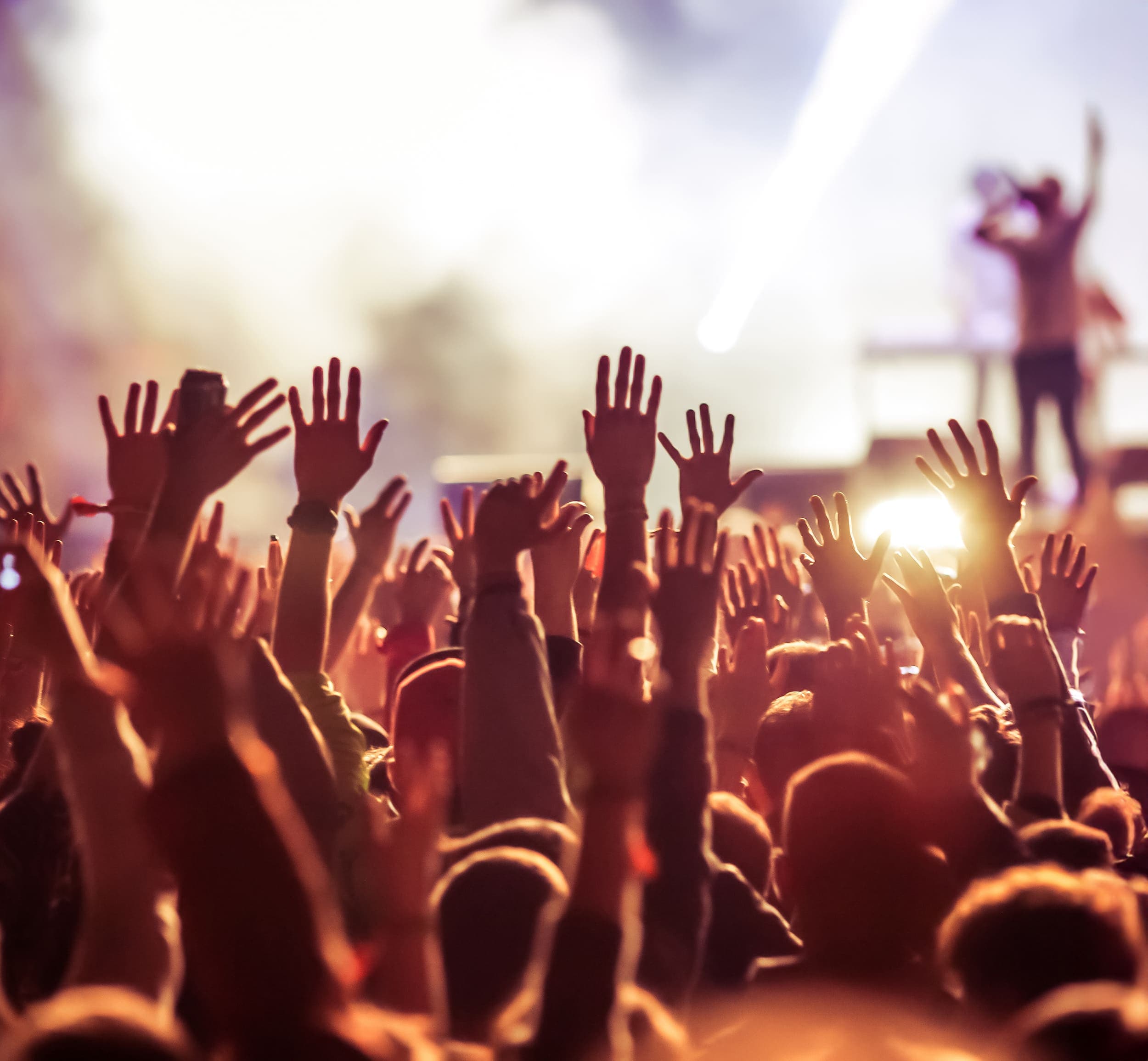 A crowd of people with their hands in the air at a concert