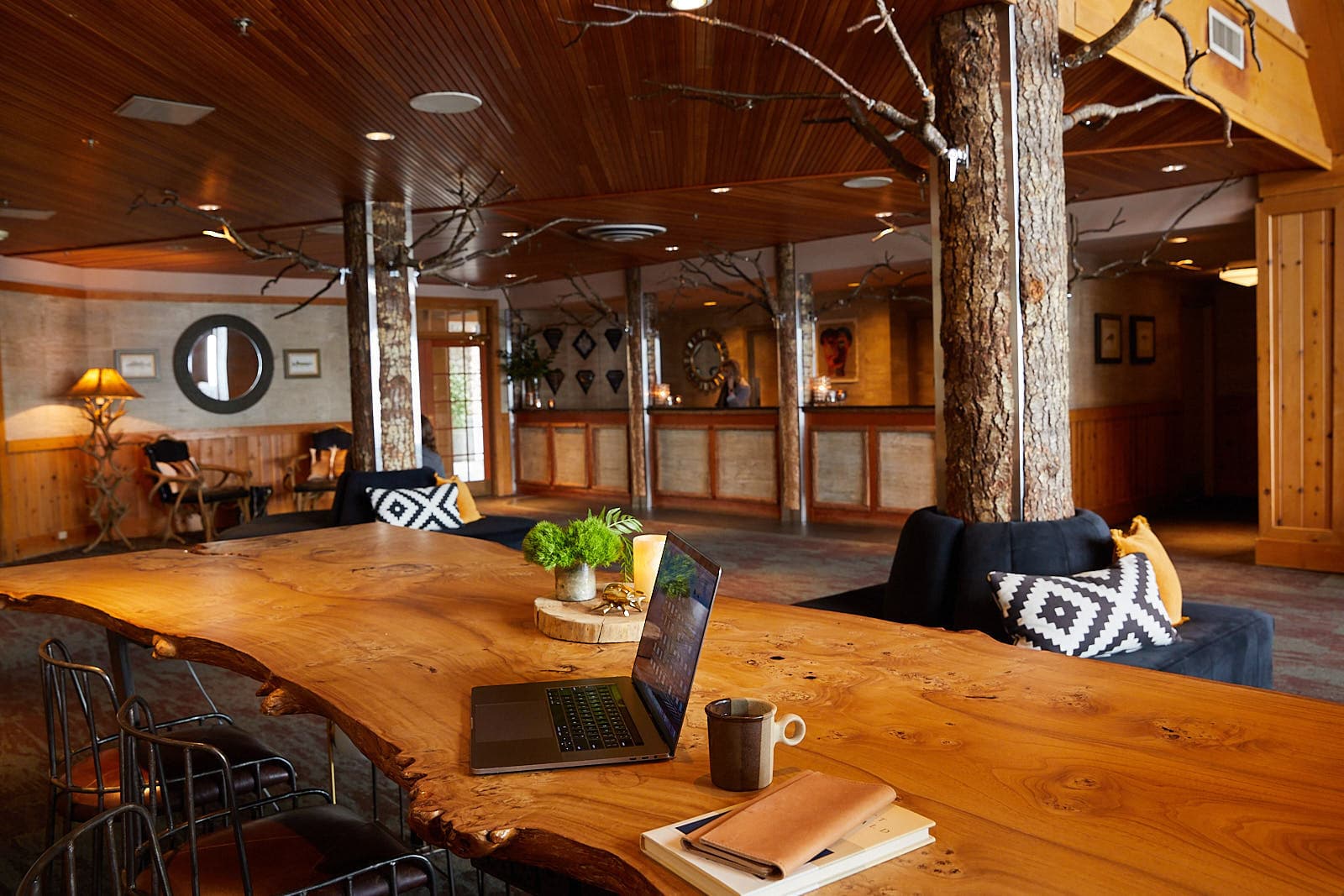 A beautiful live edge wood table in the Edgewater lobby with a laptop and coffee mug