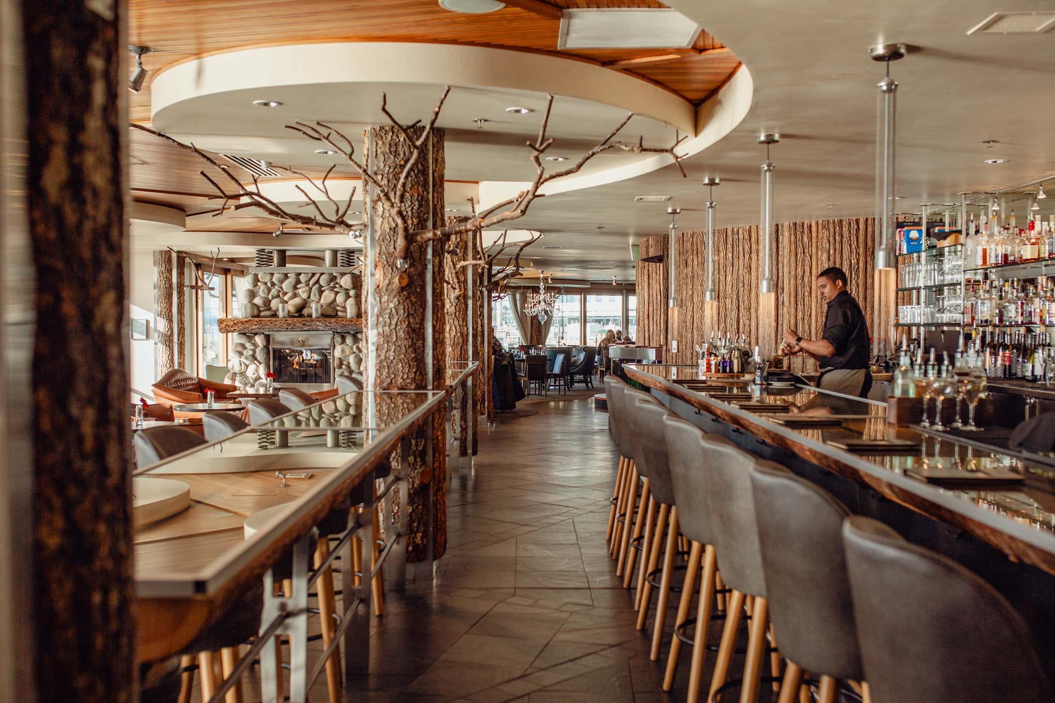 An empty Bar with beautiful decor, a stone fireplace and a bartender at Edgewater