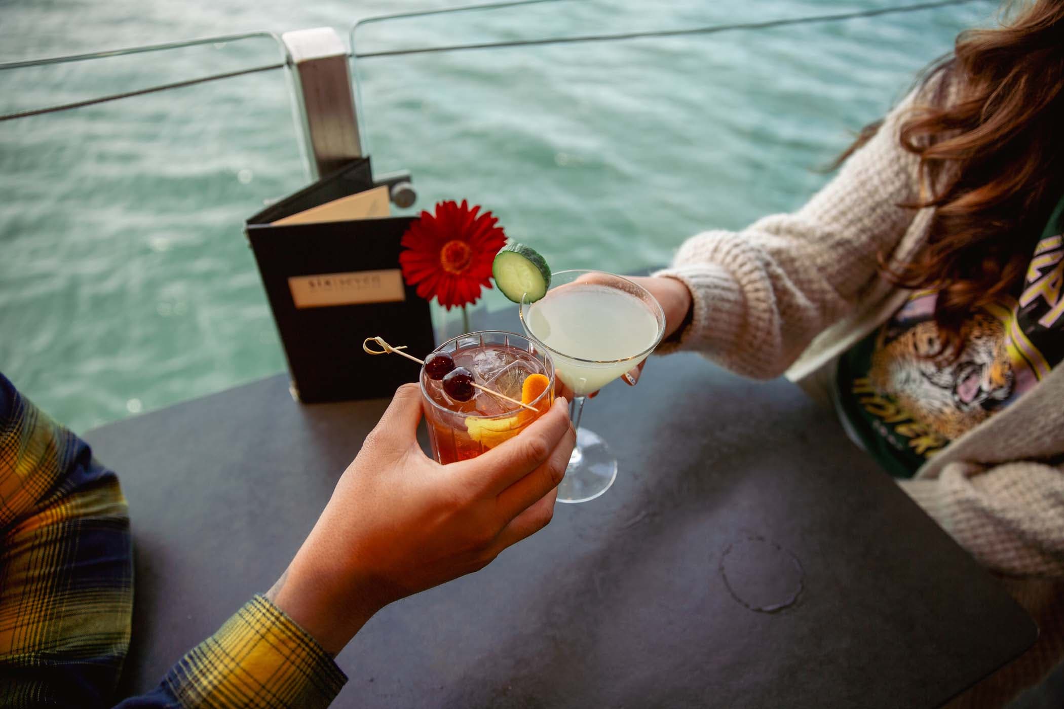 Two people sitting at a table in the bar at Edgewater having cocktails