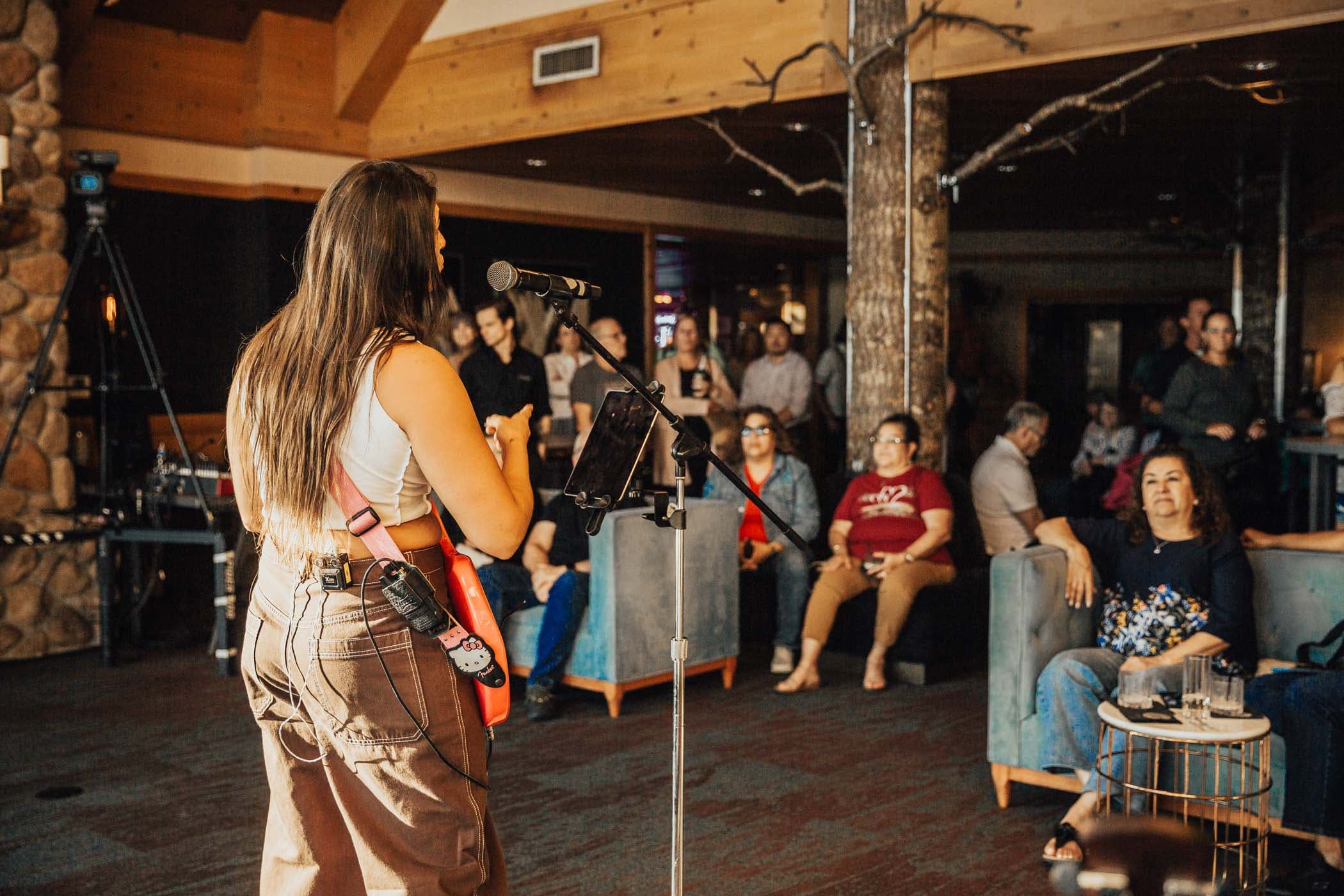 A woman playing a guitar and singing at Mariah Edge