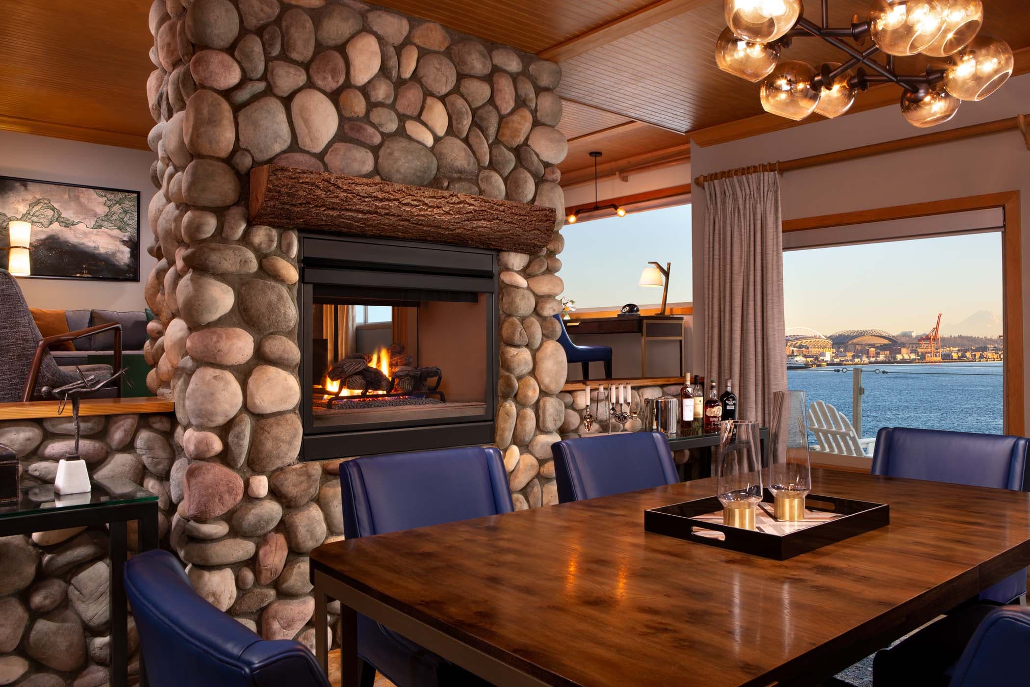 A room dividing stone fireplace and a large dining table in the Penthouse Suite at Edgewater