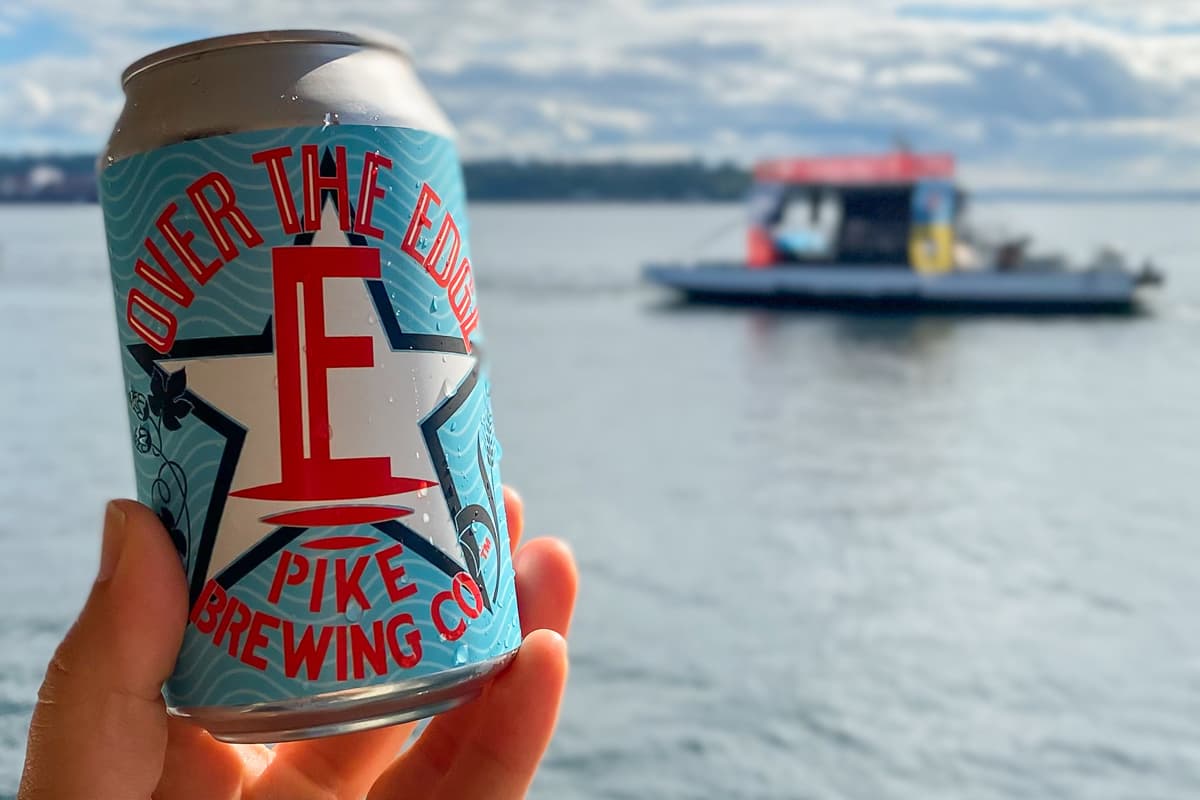 A persons hand holding a can of Over the Edge Pike Brewing Co beer
