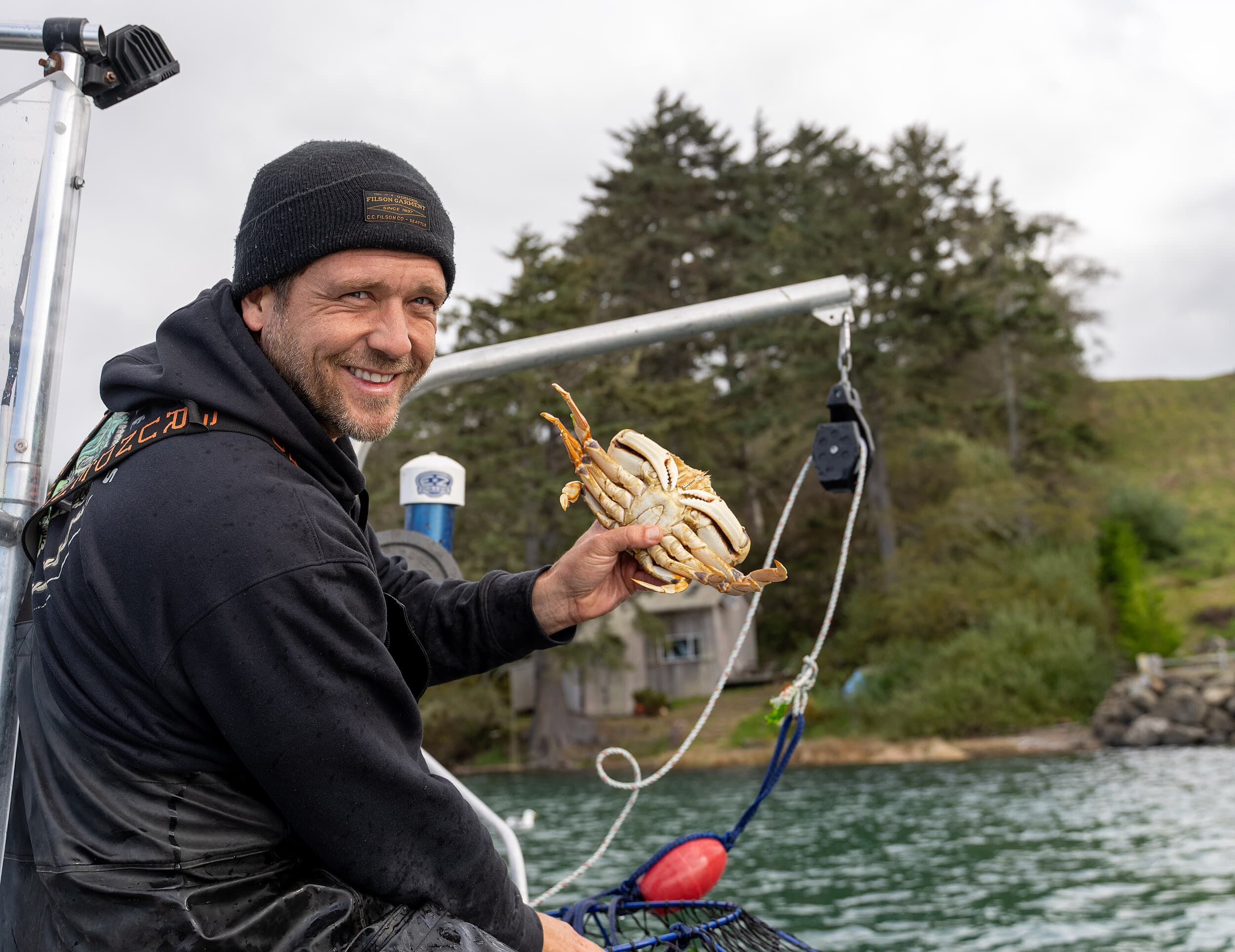 Fisherman holding a fresh Pacific Dungeness crab on a boat, showcasing local Pacific Northwest seafood served at The Edgewater Hotel in Seattle