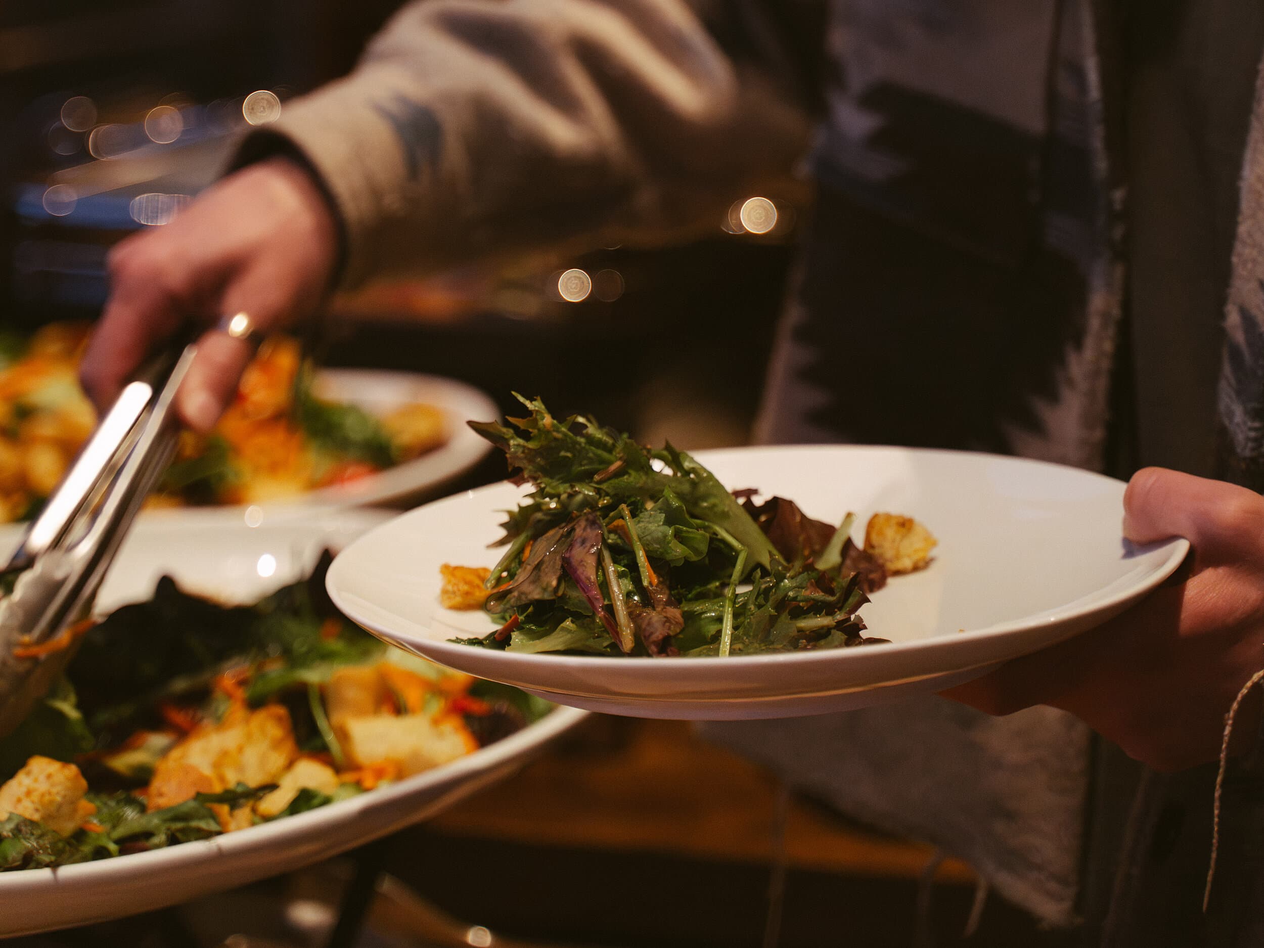 Server plating a fresh seasonal greens salad at The Edgewater Hotel's waterfront restaurant in Seattle