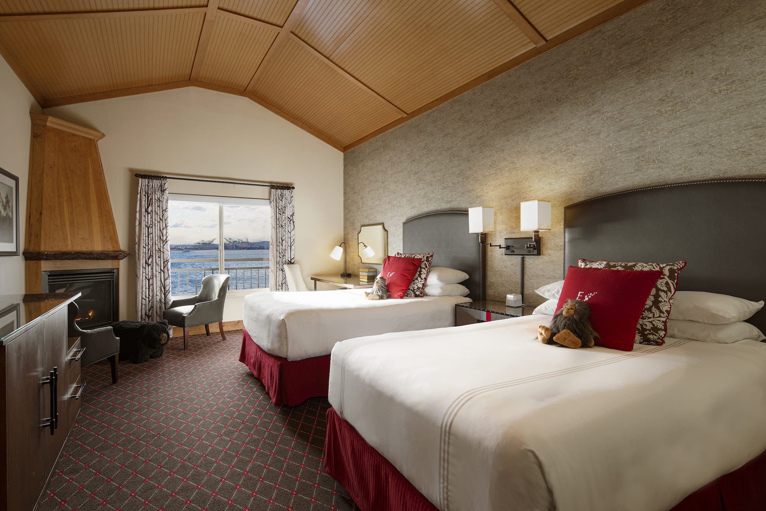 Two beds, a fireplace, with a balcony and a view of the water at Edgewater
