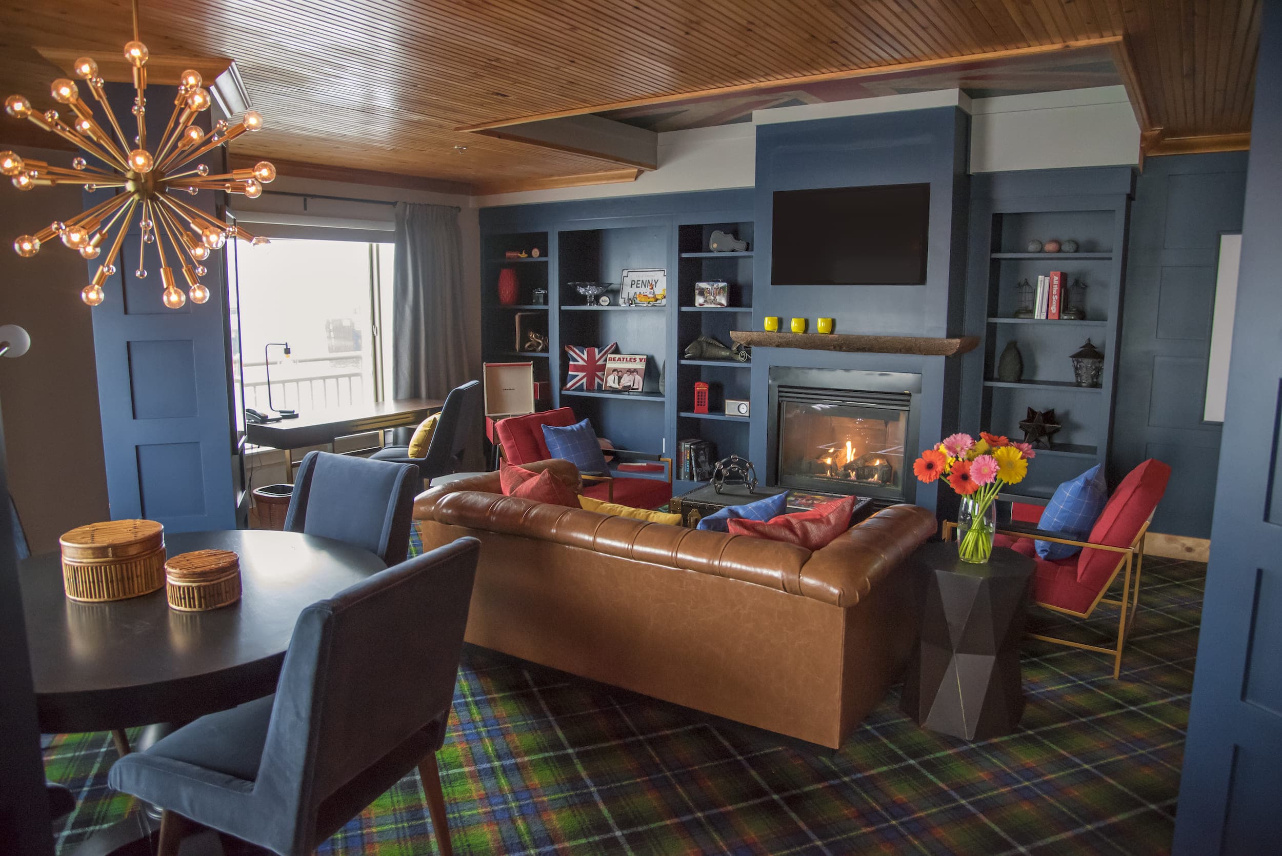 The Beatles suite at Edgewater with a round table, fireplace, lounge space with Beatles decor and flowers