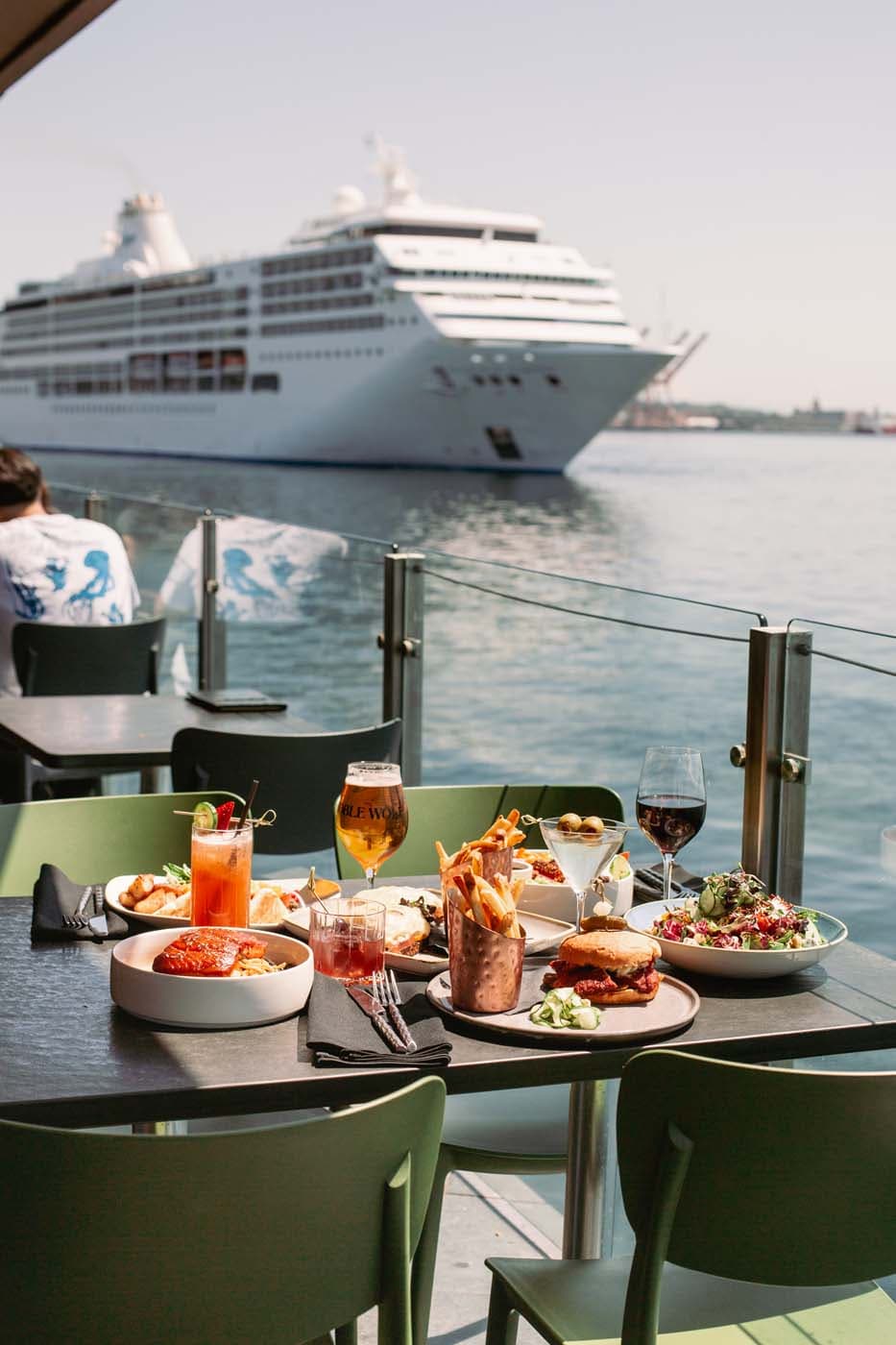 A spread of different American style dishes at Edgewater with a cruise ship in the distance