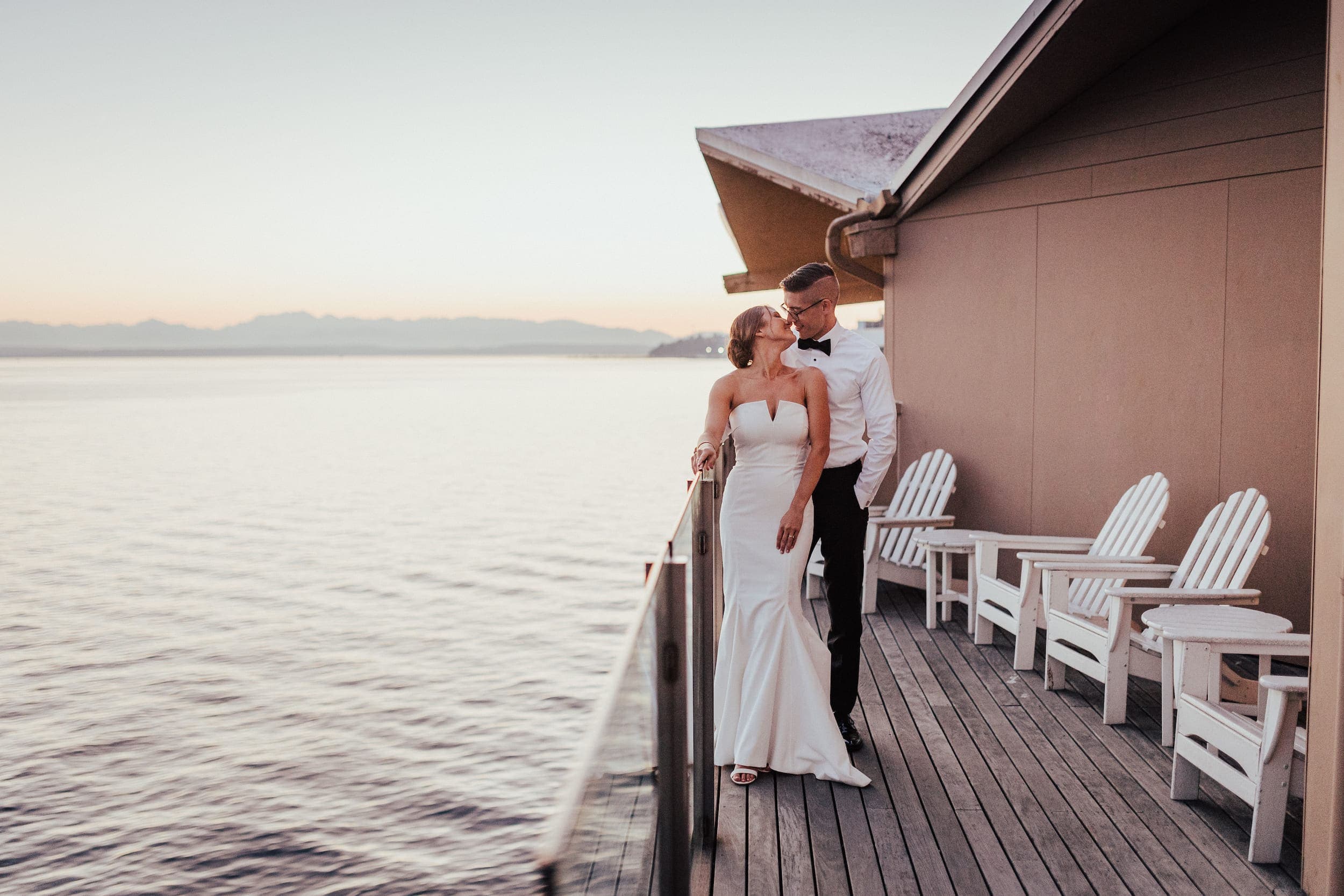 A just married couple having wedding photos taken on a patio over looking the water