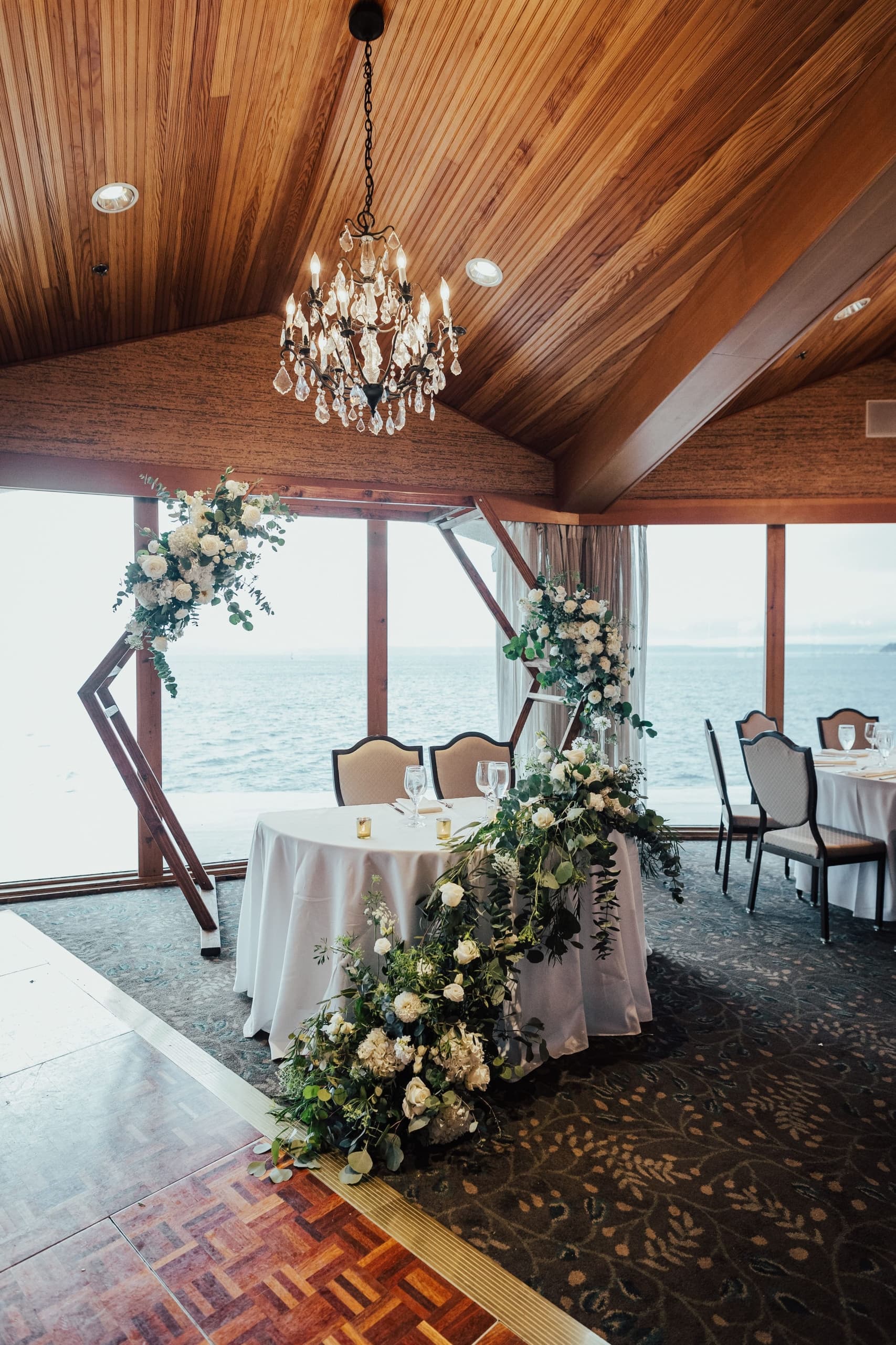 The bride and groom table decorated with beautiful bouquets of flowers with the water as the backdrop at Edgewater