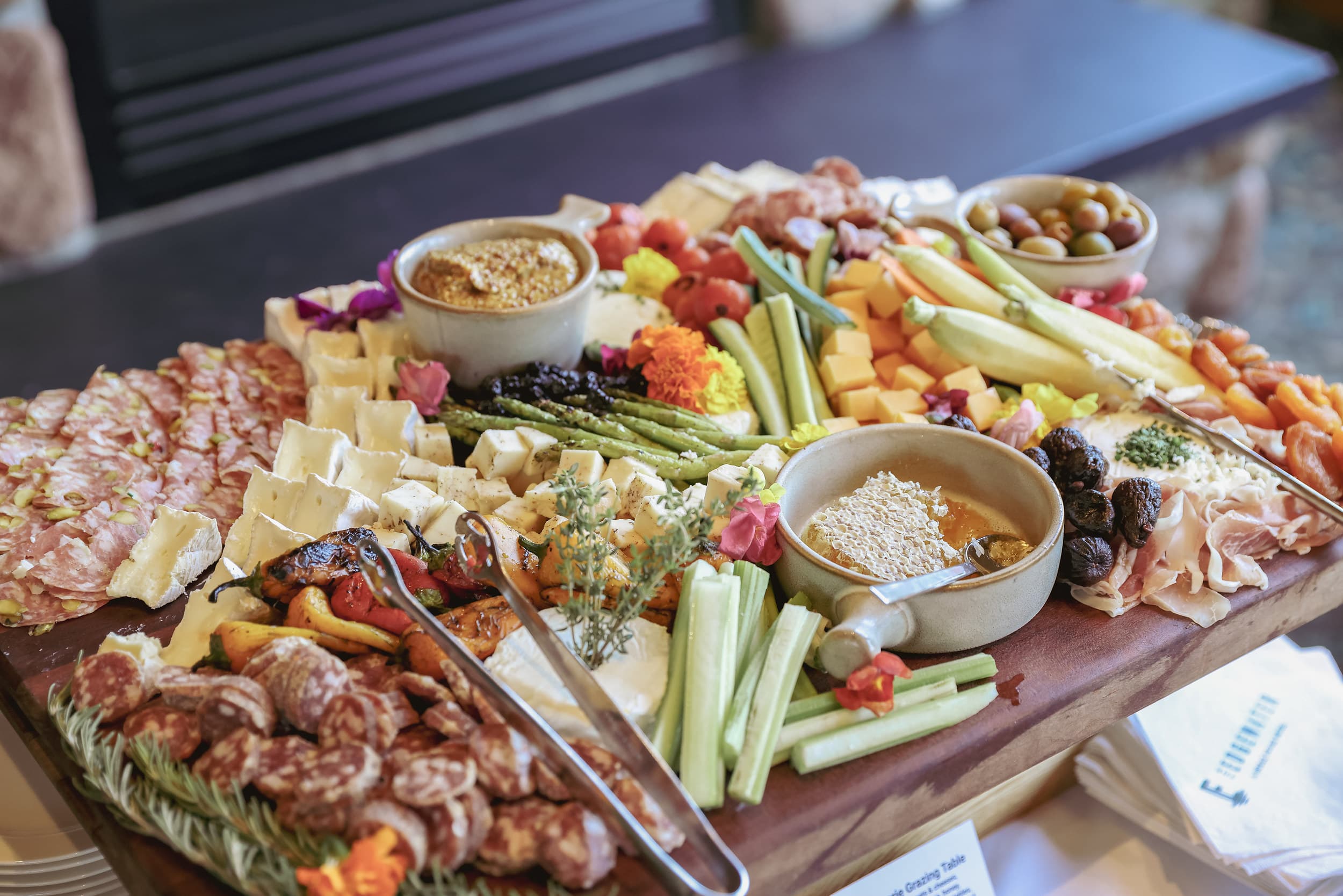 Catered charcuterie grazing table at The Edgewater Hotel Seattle featuring cured meats, artisan cheeses, honeycomb, and fresh vegetables