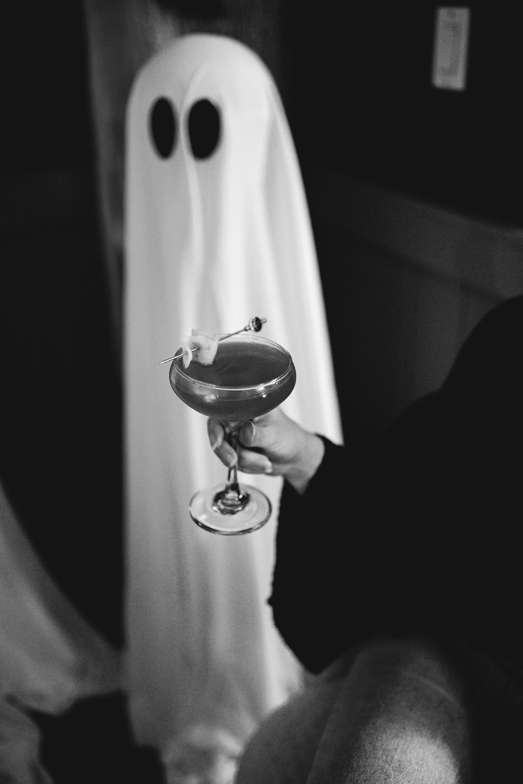 Guest in ghost costume holding a Halloween cocktail at The Edgewater Hotel bar in Seattle