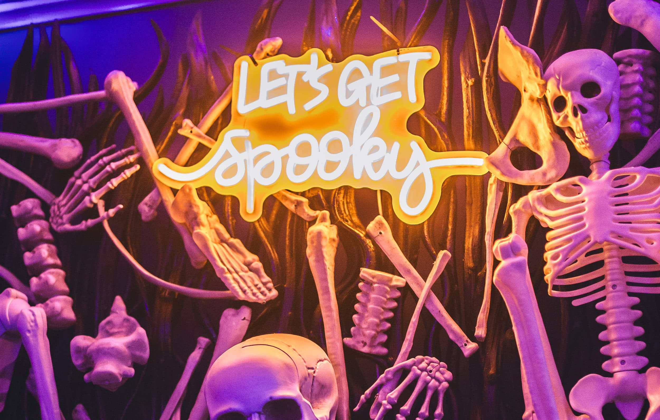 Let's Get Spooky neon sign and skeleton bone wall at The Edgewater Hotel Halloween party in Seattle