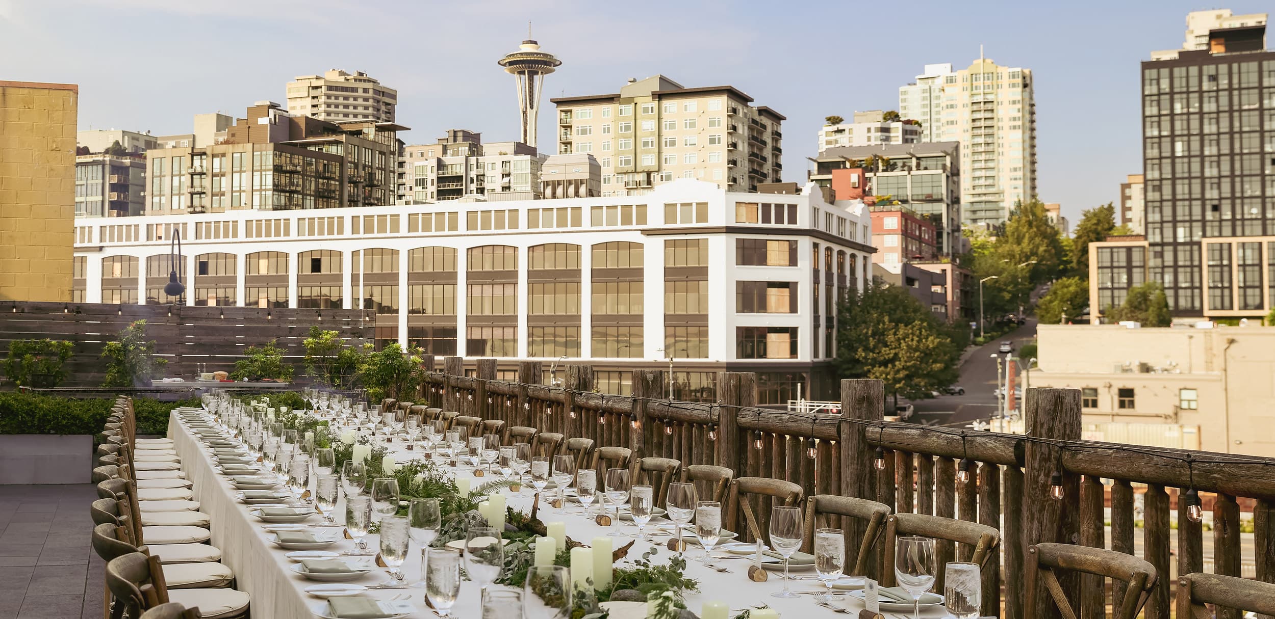 Rooftop wedding reception at The Edgewater Hotel Seattle with a long banquet table set against the Space Needle and downtown skyline