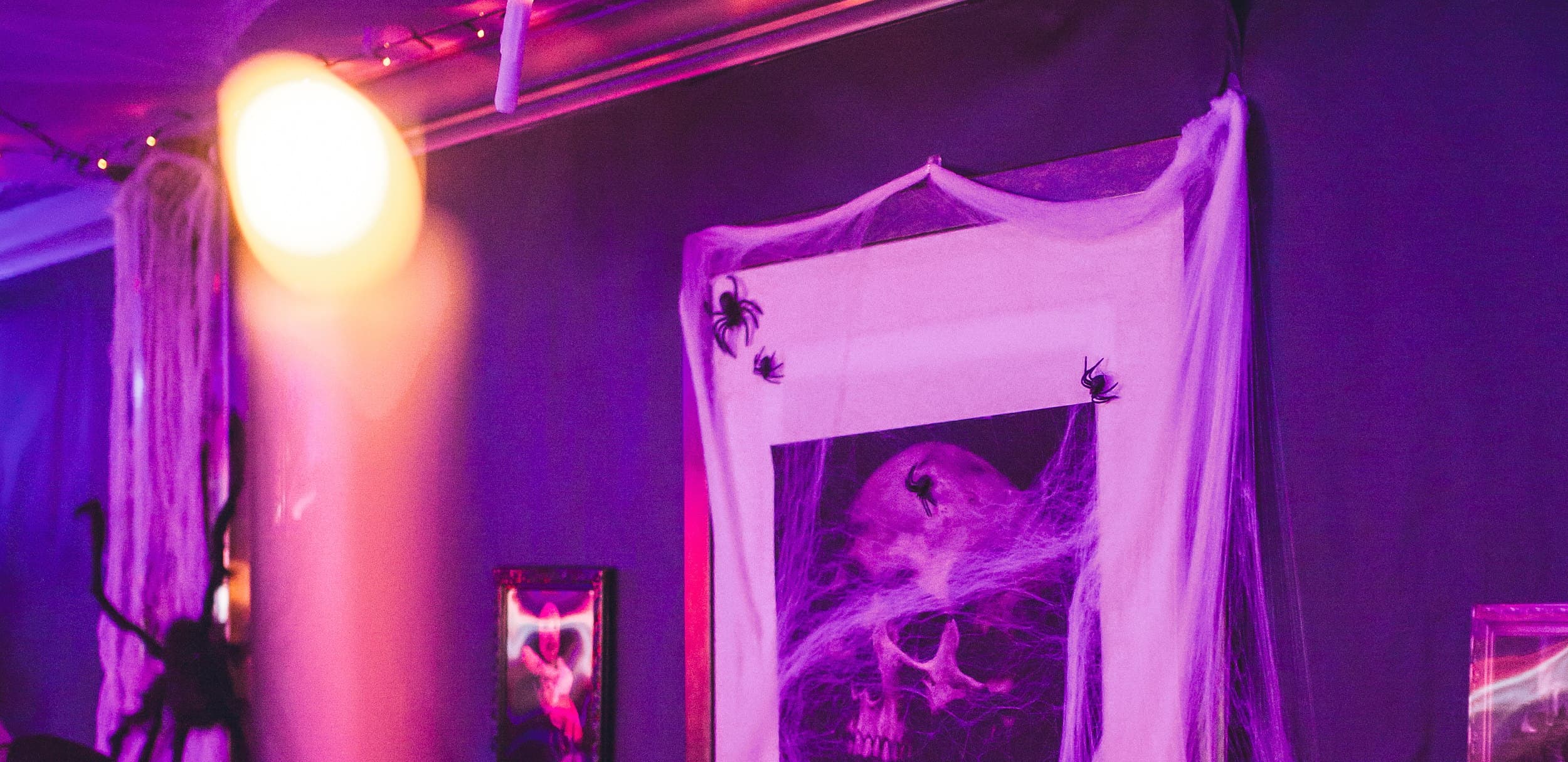 Cobweb-draped skull portrait and purple lighting at The Edgewater Hotel Halloween event in Seattle