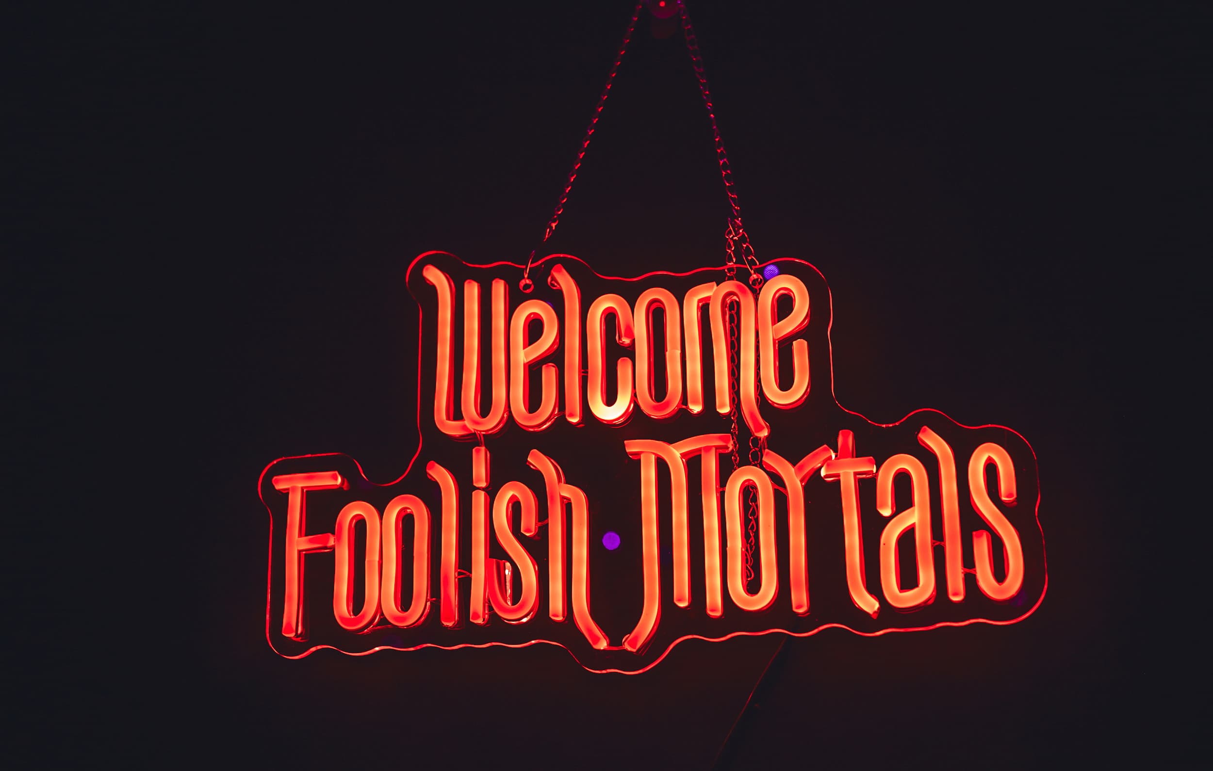 Welcome Foolish Mortals red neon sign at The Edgewater Hotel Halloween event in Seattle