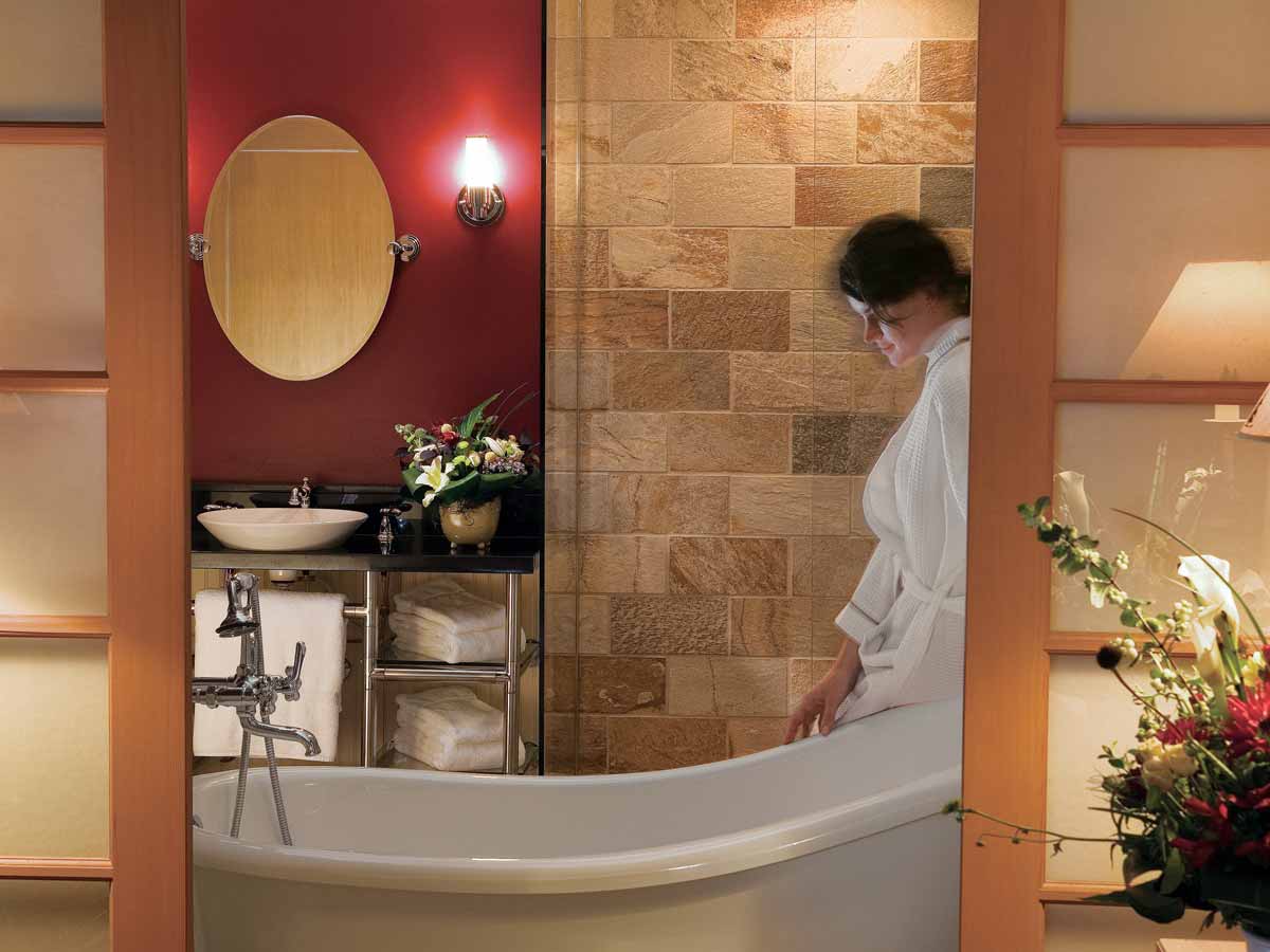 Guest room Bathroom with bath and woman in bathrobe.