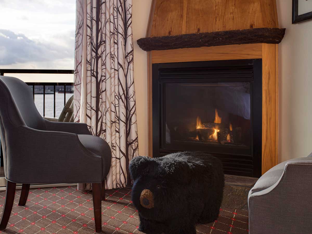Guest room sitting area with chair, fireplace and water view.