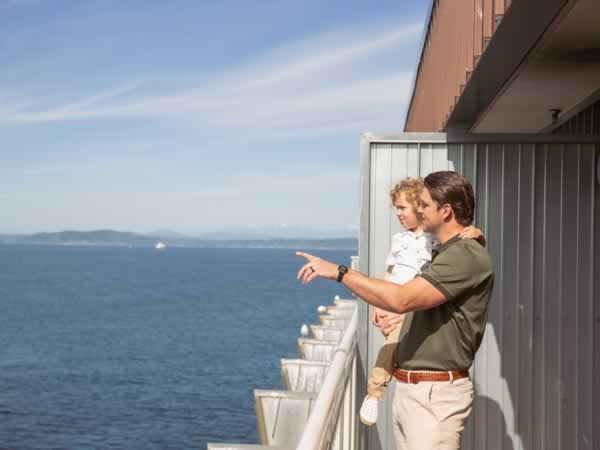 Dad holding child on waterfront balcony at the Edgewater Hotel